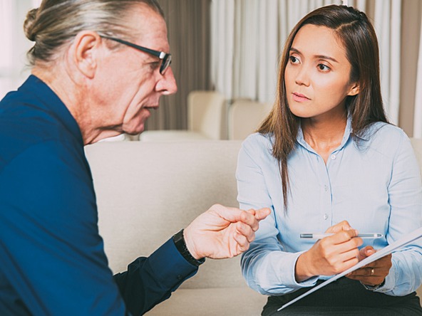 Young female researcher interviewing an older man at home